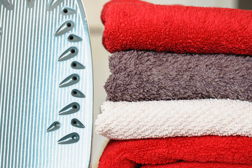 Iron for ironing on the ironing board with a pile of towels near