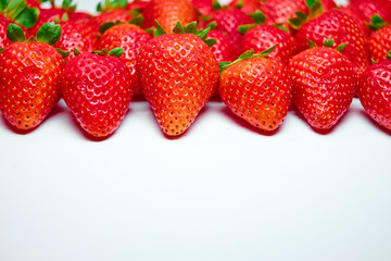 Berries of strawberries of different shapes and sizes lying in even rows on a white background