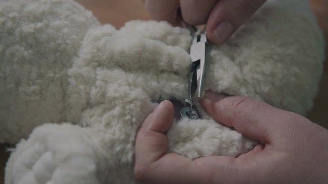 Stitching the details of a plush toy. Repair of plush toys: women's hands sew a teddy bear. Making soft toys handmade. Broken toy is a vintage bear cub - restoring an old toy.