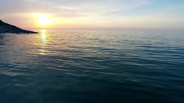 Shot of a beautiful summer sunset at the beach. Waves gently wash up onto the beach, then recede as the sunset. A beautiful sunset over a sea on Akcakoca in Turkey