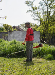 man cutting grass with hand trimmer.
