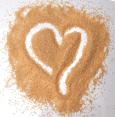 Amaranth seeds in a heart shape isolated on white background - top down view.