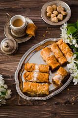 Homemade baklava rolls in iron try on wooden background. Ramadan food. Selective focus