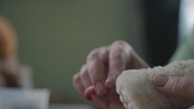 Teddy bear: the process of creation. .Details and elements of a soft plush toy: female hands sew parts of a toy. Handmade. Details of teddy bear. A rare collectible toy is a teddy bear.