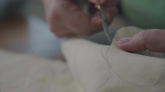 A hand-made teddy bear. The process of cutting fur for a soft toy. Teddy bear in the vintage style is an old-fashioned toy of the 20th century. The master cuts the fur to make a collectible toy.
