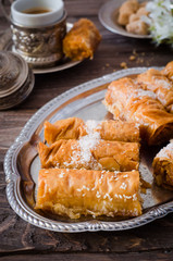 Homemade baklava rolls in iron try on wooden background. Ramadan food. Selective focus