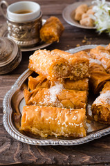 Homemade baklava rolls in iron try on wooden background. Ramadan food. Selective focus