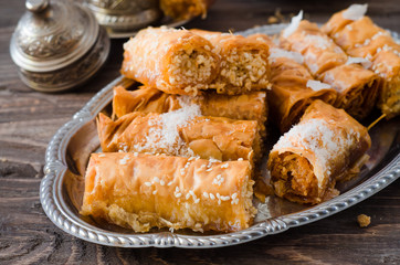Homemade baklava rolls in iron try on wooden background. Ramadan food. Selective focus