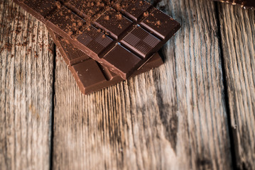 Chocolate bar pieces with cocoa powder.  Background with chocolate. Slices of chocolate,  Copyspace