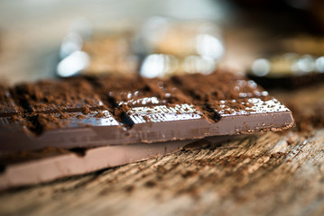 Chocolate bar pieces with cocoa powder.  Background with chocolate. Slices of chocolate,  Copyspace