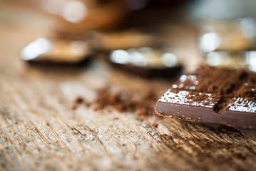 Chocolate bar pieces with cocoa powder.  Background with chocolate. Slices of chocolate,  Copyspace