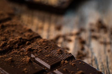 Chocolate bar pieces with cocoa powder.  Background with chocolate. Slices of chocolate,  Copyspace