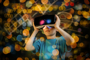 Child playing with a virtual reality headset. Young boy wearing and learning with a VR goggles.