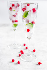 frozen red berries in ice cubes with mint in glasses on stone background