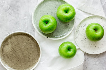 Healthy green food with apples on plates stone background top view