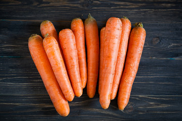 Whole carrots on dark wooden table