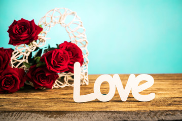 Red roses flowers with wooden word LOVE on wooden background with place for text. Romantic Valentines holidays concept. Valentine's day greeting card.. Copy space.