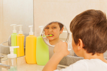 Boy looking in the glass during tooth brushing © Sergey Novikov