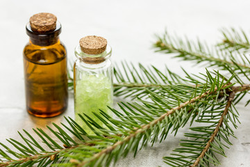 Spruce needle aromatherapy essential oils and salt in bottles on white table background