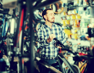Obraz premium Man considers bicycle handlebar in store