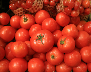 Heap of vibrant red ripe tomatoes with green stems for sale, Thailand 