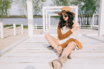 Beautiful model in hat and dress in hippie style posing on summer beach.