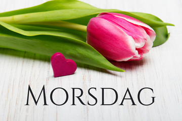 Mother's Day card with Norwegian words: Mother's Day. Tulip flowerand small heart on white wooden background. © czarny_bez