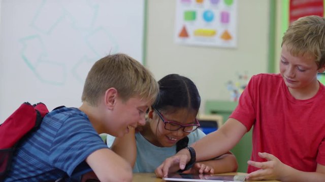 Three students having fun playing on digital tablet