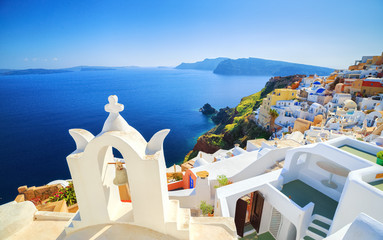 Small chapel in Oia village and traditional island-greek architecture on Santorini island, Greece, romantic resort. Sunny day scenery with blue water of Aegean sea and clear blue sky in background.