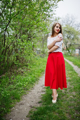 Portrait of beautiful girl with red lips at spring blossom garden, wear on red dress and white blouse.
