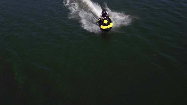 Aerial drone shot of man riding personal water craft on lake