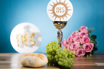 Holy Communion, chalice, flowers and grapes on wooden table