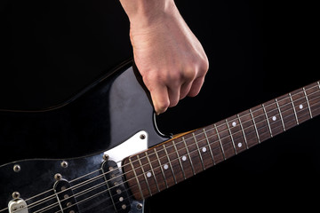 Music and art. Electric guitar in hand, on a black isolated background. Horizontal frame