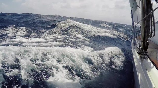 Yachting on on the sea in summer day. Yacht, boat goes through foamy blue waves at high speed, pov. Endless blue sea, in the background the horizon line