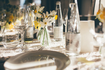 Wedding banquet on the sunset. Table for guests, decorated with candles and flowers, served with cutlery and crockery and covered with a tablecloth