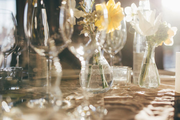 Wineglasses at sunset. Wedding banquet. Table for guests, decorated with candles and flowers, served with cutlery and crockery and covered with a tablecloth. Table decorated for the wedding reception