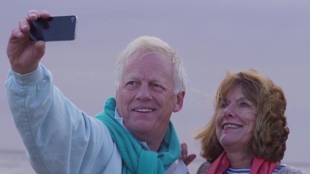 Senior couple taking selfie on beach