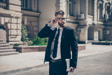 Nerdy bearded business man with tablet outside on a sunny day. He is so harsh! Wearing suit and glasses