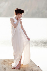 Fototapeta na wymiar girl in white dress standing on a wodden pier