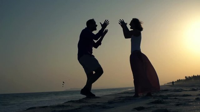 Silhouette of couple fighting on beach during sunset, super slow motion 240fps
