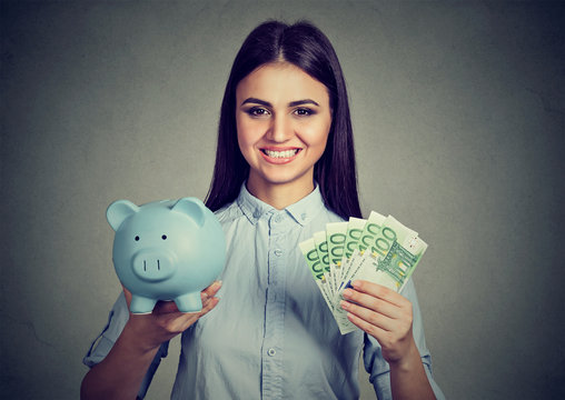 woman smiling, holding piggy bank and hundred euro banknotes