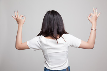 Back view of Asian woman show double OK hand sign.