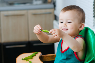 Mixed race girl shelling pea pod at dining table
