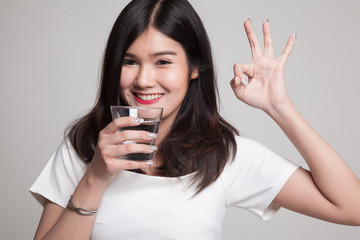 Young Asian woman show OK with a glass of drinking water.