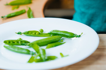 Mixed race girl shelling pea pod at dining table