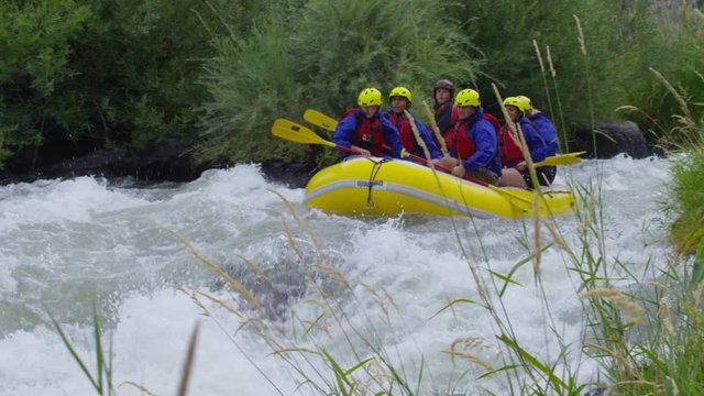 Group of people white water rafting in slow motion