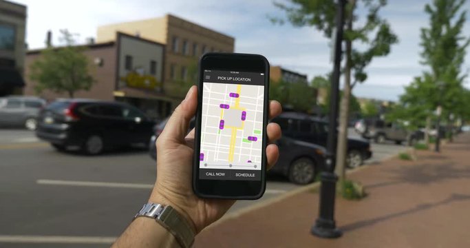 A man holds his smartphone to observe ride sharing traffic patterns on an interactive map in a small city.	