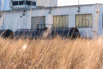 Fototapeta na wymiar old industrial factory with train car and prairie grass