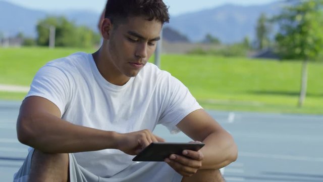 Teen basketball player using digital tablet at outdoor court