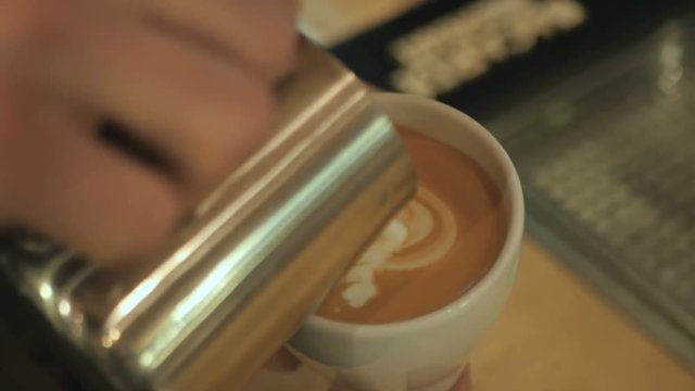 The barman drawing on the coffee with milk